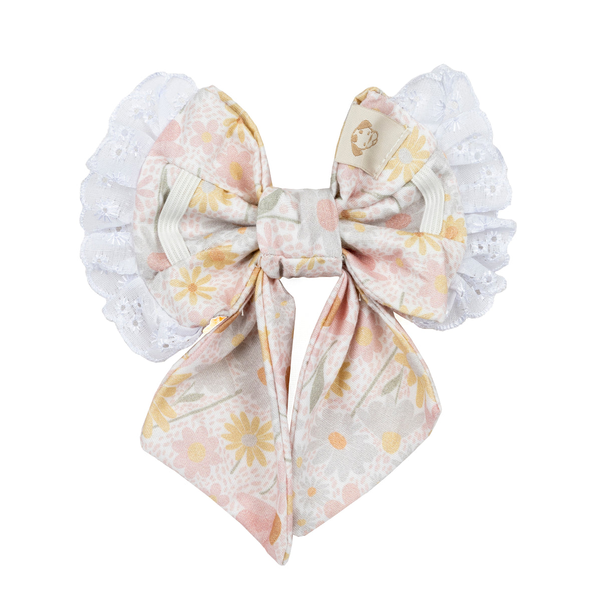 A decorative bow dog clip featuring a central floral printed fabric bow in soft pastel pink, yellow, and beige, flanked by white ruffled lace side wings, shown on a plain white background.